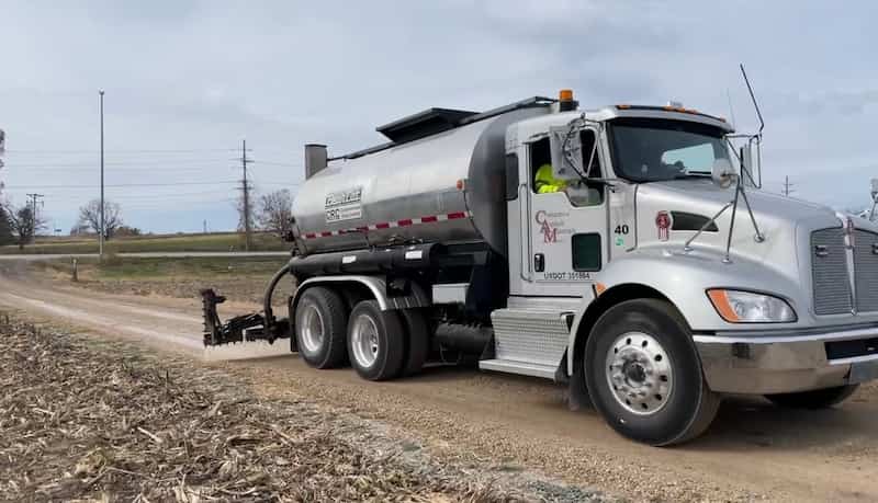 Dust control is sprayed onto gravel road